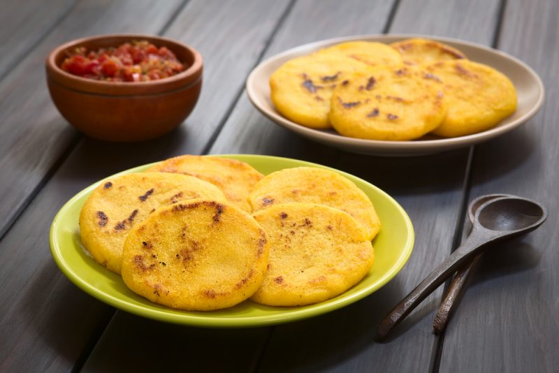 Two plates of arepas with Colombian hogao sauce